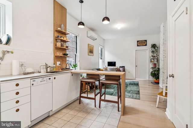 kitchen featuring dishwasher, light wood-type flooring, pendant lighting, backsplash, and white cabinets