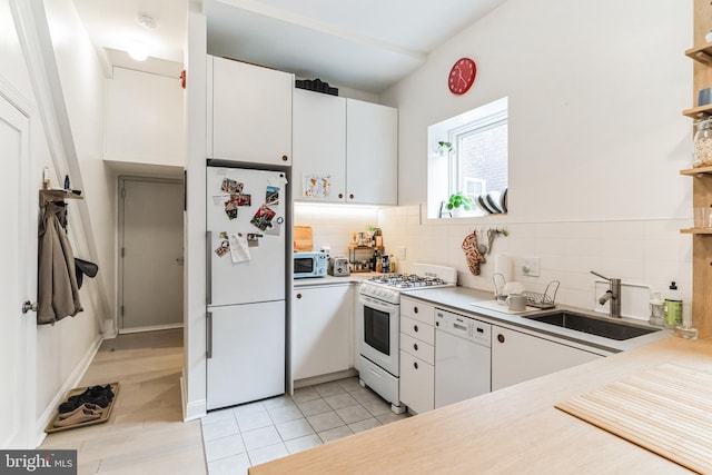 kitchen featuring sink, white appliances, white cabinets, and tasteful backsplash