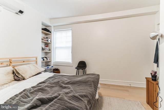 bedroom featuring hardwood / wood-style floors and a wall mounted AC