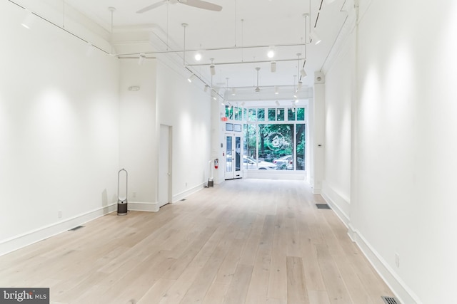 hallway with expansive windows, a high ceiling, and light wood-type flooring