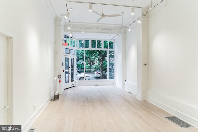 spare room with a high ceiling, ceiling fan, and light hardwood / wood-style flooring