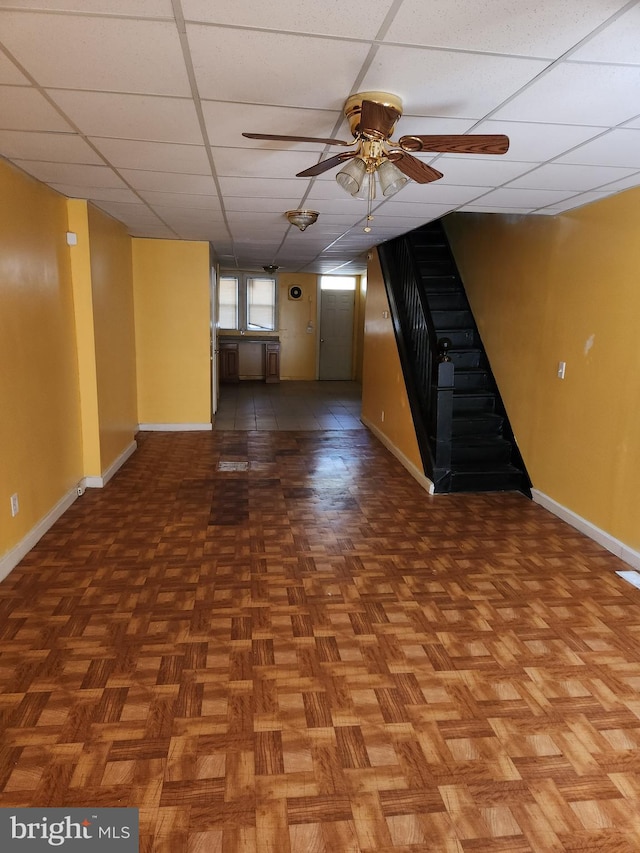 unfurnished living room featuring a paneled ceiling, parquet flooring, and ceiling fan