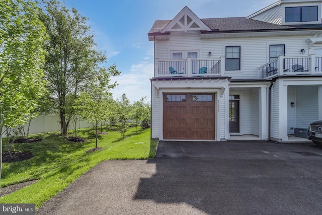 view of front of home featuring a garage, a front yard, and a balcony