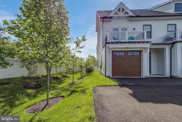 view of side of home with a garage, a balcony, and a yard