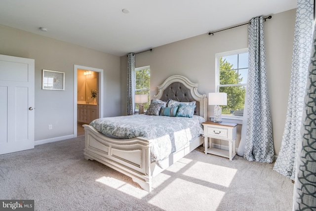 bedroom featuring light carpet and ensuite bath