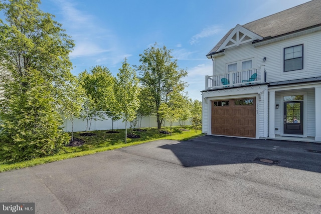 view of side of home featuring a garage and a balcony