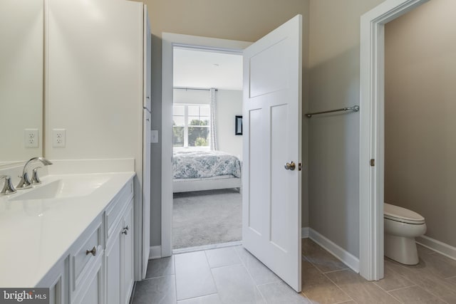 bathroom featuring tile flooring, vanity, and toilet