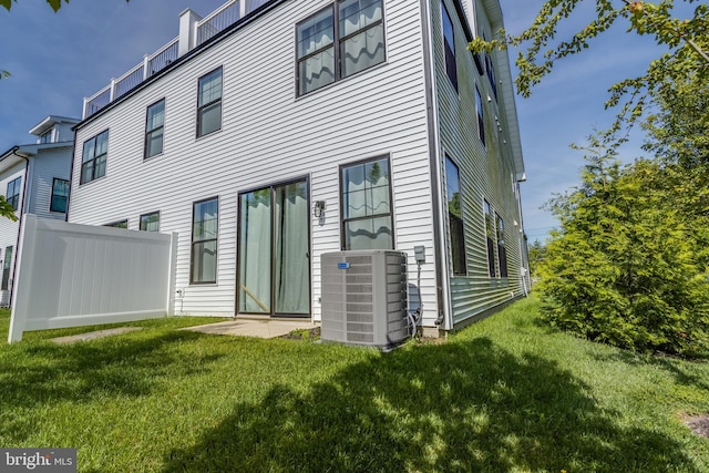 rear view of house featuring central air condition unit and a yard