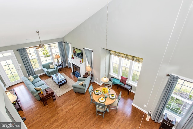 living room with high vaulted ceiling, ceiling fan, a healthy amount of sunlight, and hardwood / wood-style flooring