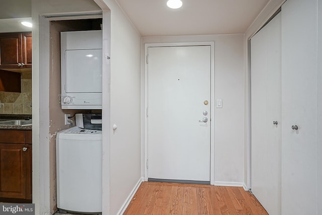 laundry room with light hardwood / wood-style floors and stacked washer / dryer