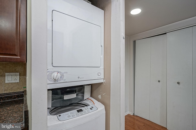 washroom with light hardwood / wood-style floors and stacked washer / dryer