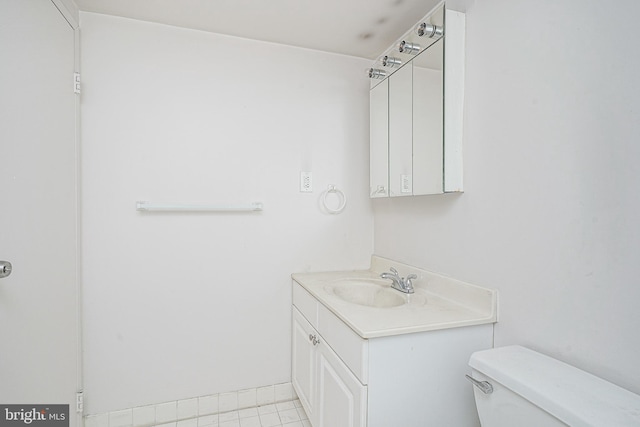 bathroom with tile flooring, toilet, and vanity with extensive cabinet space