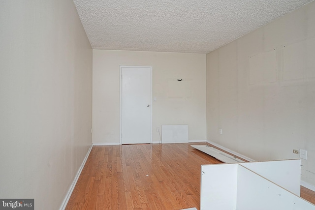 spare room with light hardwood / wood-style floors and a textured ceiling