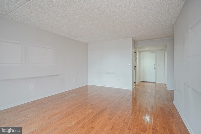 spare room with a textured ceiling and light wood-type flooring