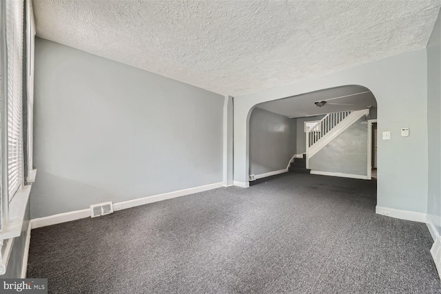 spare room with dark colored carpet and a textured ceiling