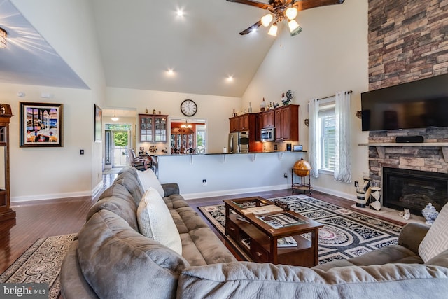 living room with high vaulted ceiling, ceiling fan, hardwood / wood-style flooring, and a fireplace