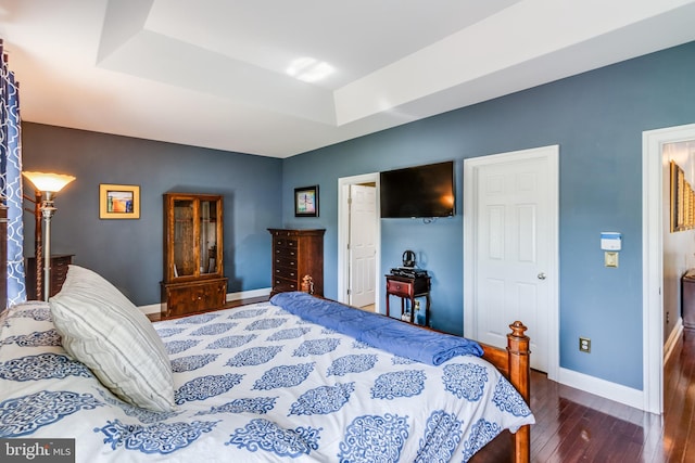 bedroom with a tray ceiling and dark hardwood / wood-style floors