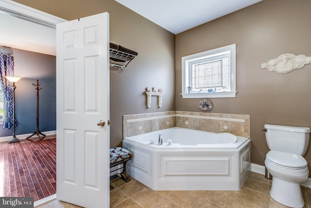 bathroom with a bath to relax in, tile flooring, and toilet