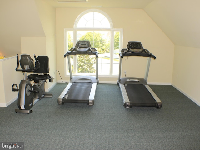 workout area featuring lofted ceiling and dark colored carpet