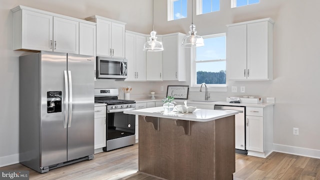 kitchen with pendant lighting, plenty of natural light, light hardwood / wood-style flooring, and stainless steel appliances