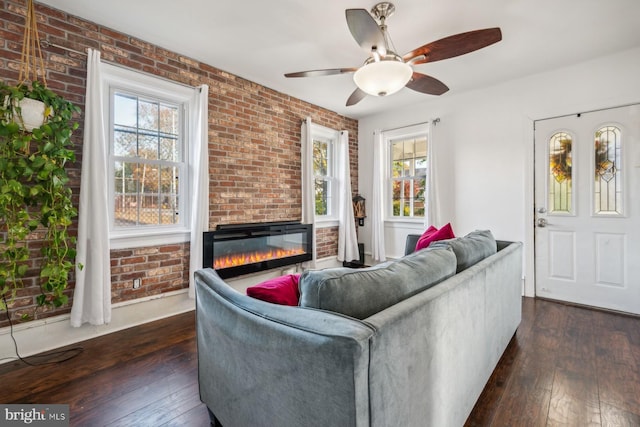 living room with ceiling fan, dark hardwood / wood-style floors, and brick wall