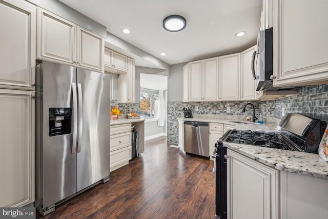 kitchen featuring sink, decorative backsplash, appliances with stainless steel finishes, light stone countertops, and dark hardwood / wood-style flooring