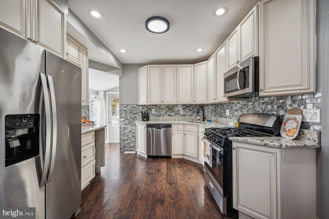 kitchen featuring stainless steel appliances, light stone counters, white cabinets, dark wood-type flooring, and decorative backsplash