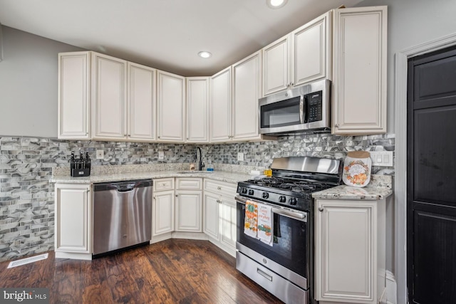 kitchen featuring appliances with stainless steel finishes, light stone counters, and dark hardwood / wood-style floors