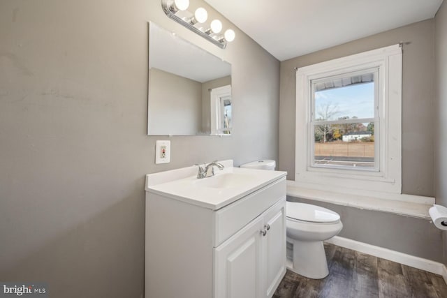 bathroom with toilet, vanity, and wood-type flooring