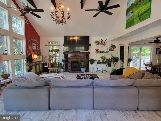 living room with a brick fireplace, an inviting chandelier, high vaulted ceiling, and light wood-type flooring