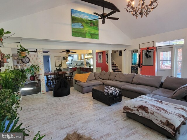 living room with high vaulted ceiling, ceiling fan with notable chandelier, and light wood-type flooring