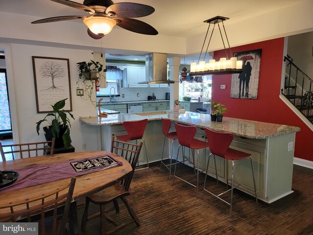 kitchen with hanging light fixtures, kitchen peninsula, backsplash, and exhaust hood