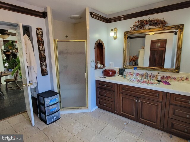 bathroom featuring tile patterned floors, vanity, a shower with shower door, and ornamental molding