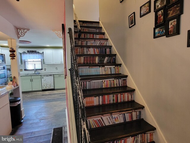 staircase with hardwood / wood-style floors and sink