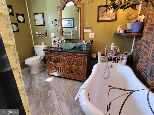 bathroom featuring vanity, toilet, wood-type flooring, and a tub