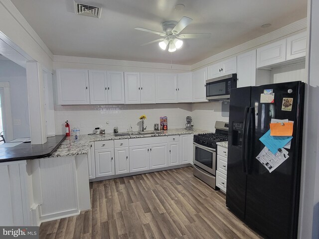 kitchen with appliances with stainless steel finishes, ceiling fan, crown molding, white cabinets, and hardwood / wood-style floors