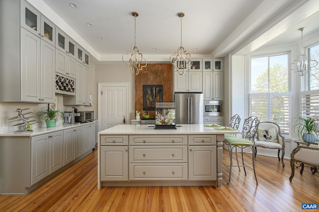 kitchen with hanging light fixtures, a center island, light hardwood / wood-style flooring, and appliances with stainless steel finishes