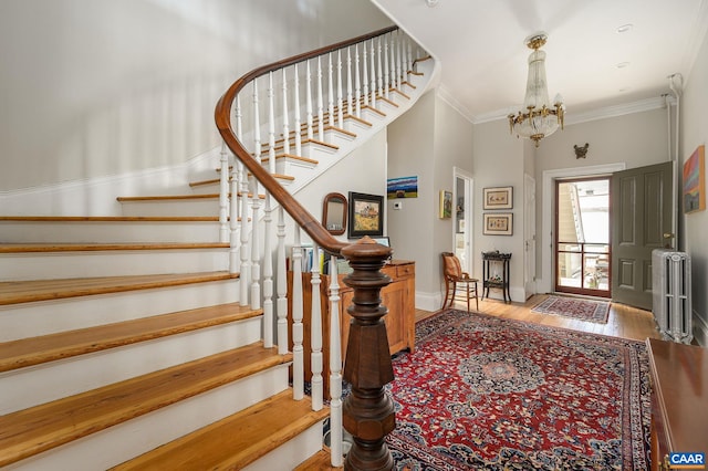 entrance foyer featuring crown molding, hardwood / wood-style flooring, radiator heating unit, and a notable chandelier