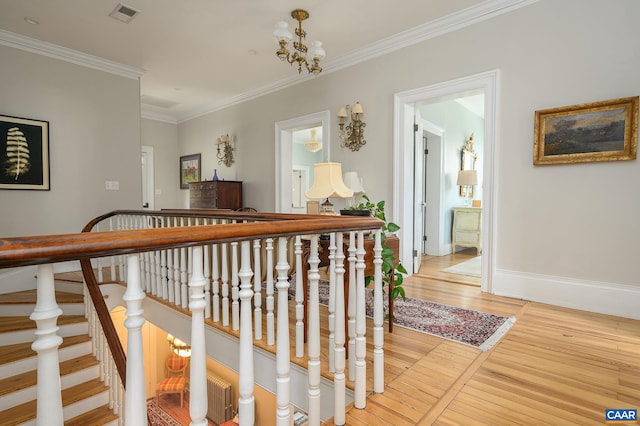 hallway with crown molding, light wood-type flooring, and a chandelier