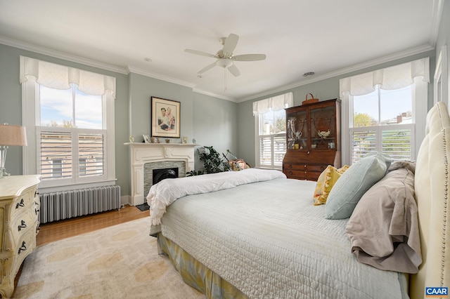 bedroom with crown molding, hardwood / wood-style floors, radiator, and ceiling fan