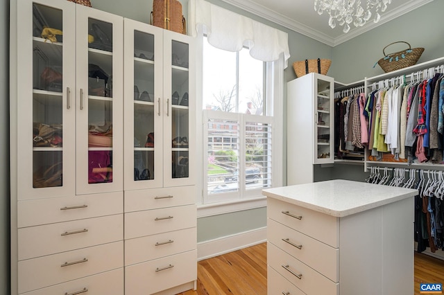 spacious closet with an inviting chandelier and light wood-type flooring