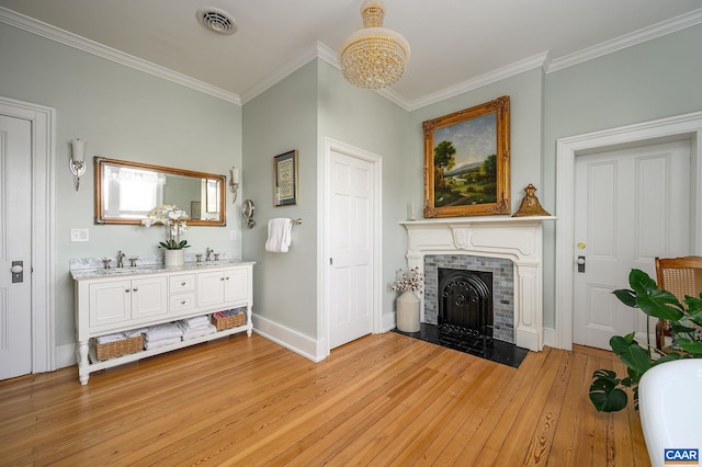 living room featuring sink, light hardwood / wood-style flooring, crown molding, and a tile fireplace