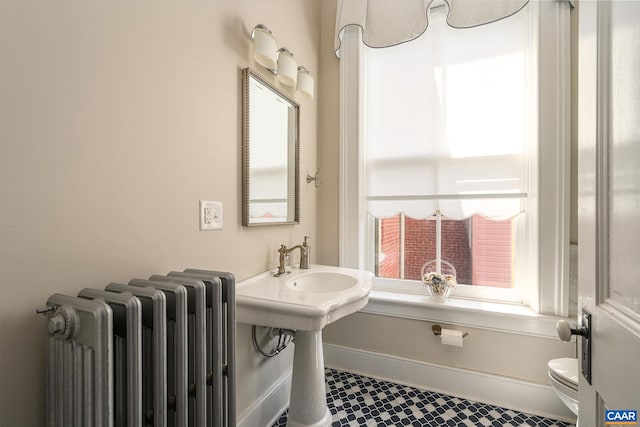 bathroom with tile floors, radiator, and toilet