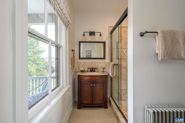 bathroom with walk in shower, radiator, tile floors, backsplash, and vanity