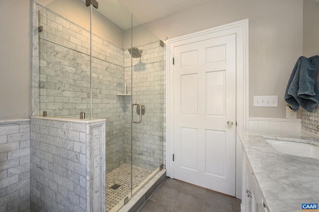 bathroom featuring a shower with shower door, tile flooring, and vanity