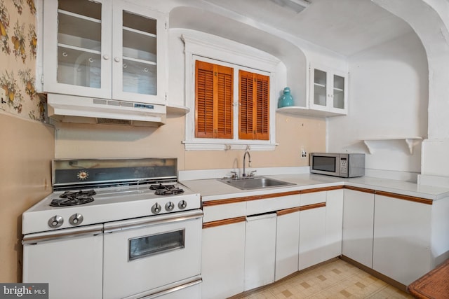 kitchen with sink, white cabinets, light tile flooring, and range with two ovens