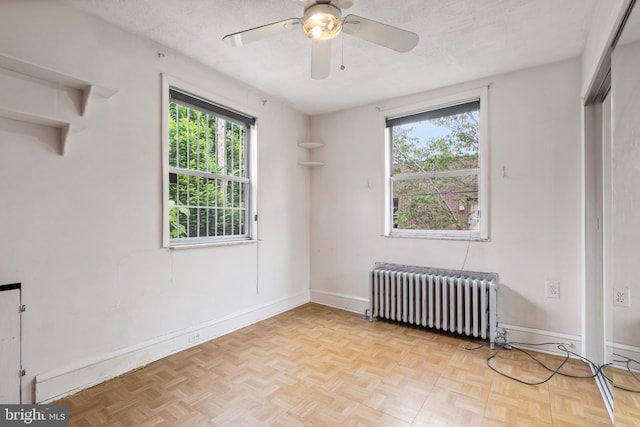 empty room with a textured ceiling, radiator, and light parquet floors