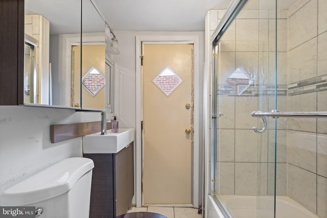 full bathroom with tile floors, sink, bath / shower combo with glass door, and toilet