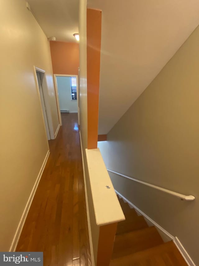 staircase with a baseboard heating unit and dark wood-type flooring