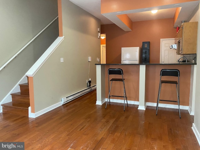 kitchen with hardwood / wood-style flooring, baseboard heating, and kitchen peninsula